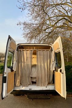 an old van is parked on the side of the road in front of a tree