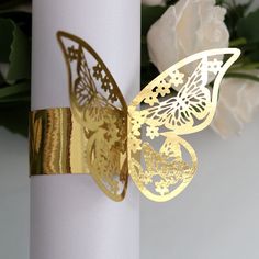 a close up of a white pillar with a gold butterfly decoration on it and flowers in the background