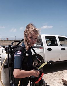 a woman in scuba gear standing next to a white truck with a hose attached to it