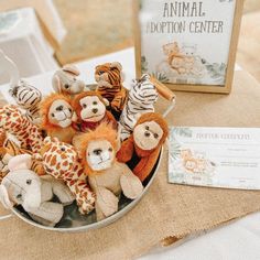 several stuffed animals in a metal bowl on a table next to a sign that says animal adoption center