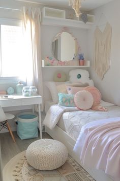 a bedroom with a white bed, pink and blue decor and a round ottoman on the floor