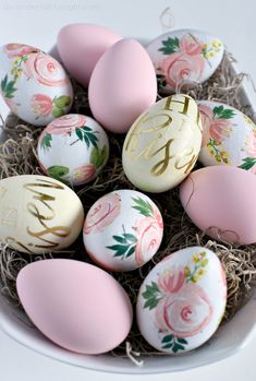 an arrangement of painted eggs in a bowl with the word monogrammed on them