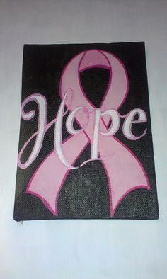 a pink ribbon with the word hope painted on it is displayed in front of a white wall