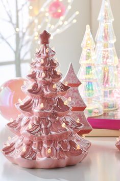 a pink christmas tree sitting on top of a white table next to other holiday decorations