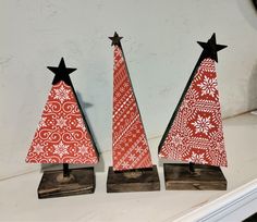 three red and white christmas trees sitting on top of a shelf