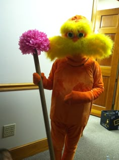 a person in an orange outfit holding a pink and yellow pom - pom