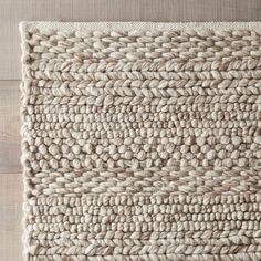 an area rug made out of jute on top of a wooden floor with white and beige colors