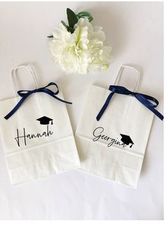 two personalized graduation gift bags tied to each other with blue ribbon and white flowers