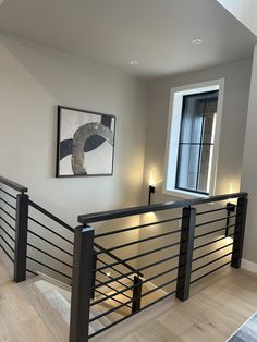 an empty living room with stairs leading up to the second floor and a painting on the wall