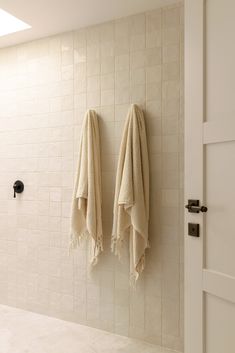 two towels are hanging on the wall next to each other in a white tiled bathroom