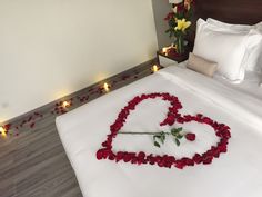 a bed with rose petals in the shape of a heart