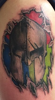 a tattoo on the back of a man's shoulder with a spartan helmet painted on it