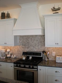 a stove top oven sitting inside of a kitchen next to white cabinets and counter tops