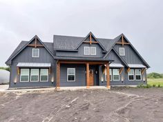 a large gray house sitting on top of a dirt field