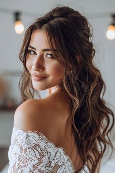 a beautiful woman with long hair wearing a white dress and smiling at the camera while standing in front of some lights