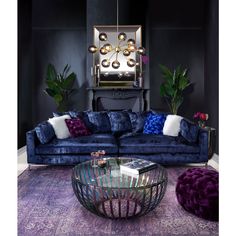 a living room with blue velvet couches, purple rugs and large mirror on the wall