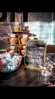 a table topped with lots of cupcakes next to a chalkboard sign that says cotton candy sweet is low for me