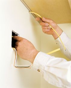 a person is plugging wires into an electrical outlet on the wall in their home