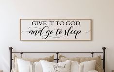 a bed with pillows and a sign above it that says give it to god and get to sleep