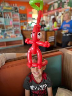 a young boy sitting in a booth with an inflatable balloon attached to his head