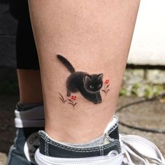 a black cat with red flowers on it's leg is seen from the side