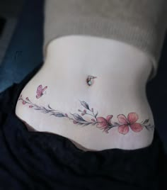 a woman's stomach with pink flowers and butterflies on the bottom part of her belly