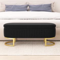 a white bed with black and gold foot stools in front of it on carpeted floor