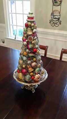 a christmas tree made out of ornaments sitting on top of a wooden dining room table