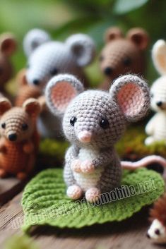 small crocheted mouses sitting on top of a green leafy surface with leaves