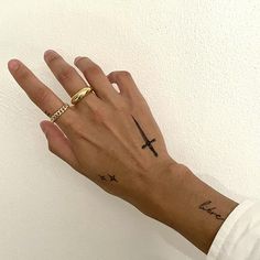 a person's hand with a cross tattoo on it