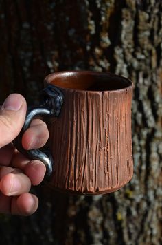 a person holding a coffee mug in front of a tree