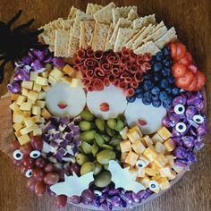 a platter filled with grapes, crackers, cheeses and other food items