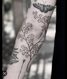 a woman's arm with flowers and butterflies tattooed on the back of her arm