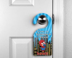 a door hanger that says come in, superhero in training with a cartoon character on it