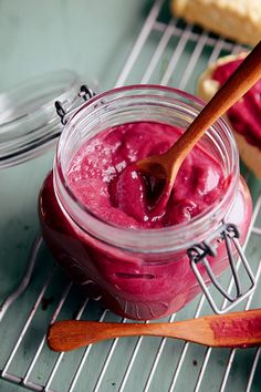 a jar filled with red liquid sitting on top of a metal rack next to cookies