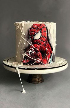 a spiderman cake with white frosting and sprinkles on the top