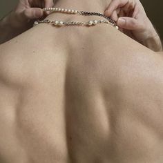 the back of a man's neck with pearls attached to his arm and hand