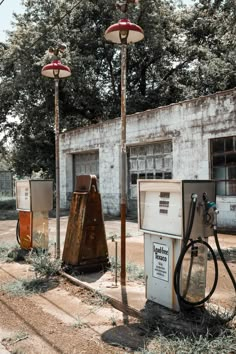 an old gas station with three different types of fueling pumps and one is empty