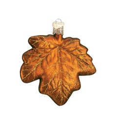 an ornament shaped like a leaf with gold glitters on it's surface