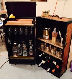 an old fashioned liquor cabinet is filled with bottles and glasses, including one empty bottle