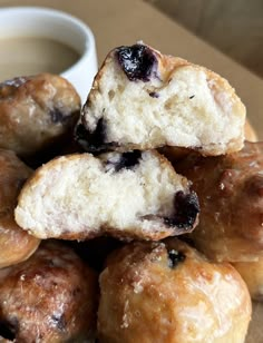 a pile of blueberry donuts next to a cup of coffee