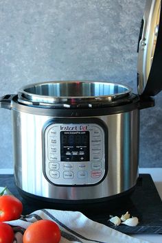 an instant pot with the lid open next to tomatoes