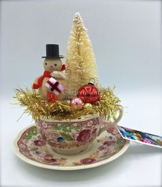 a teacup filled with ornaments and a snowman figurine