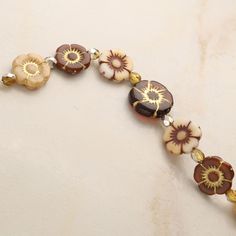 a close up of a bracelet with flowers on the side and beads attached to it