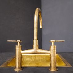 a brass faucet with two handles and nozzles on a black surface