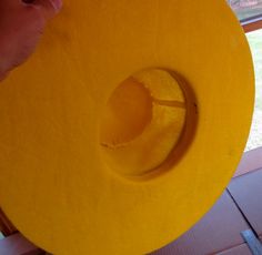 a person holding a yellow hat on top of a wooden table next to a window