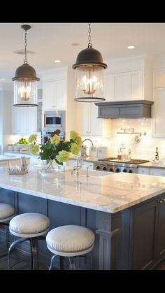 a kitchen island with stools and lights hanging from it's ceiling over the sink