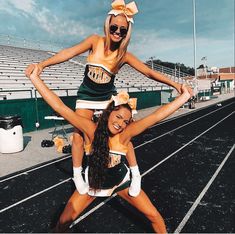 two cheerleaders are posing on the track