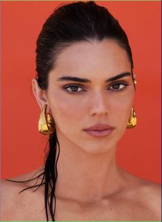 a woman with long hair wearing gold earrings