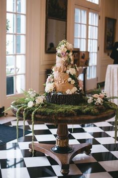 a wedding cake sitting on top of a black and white checkered tablecloth covered floor